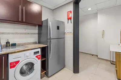a kitchen with a refrigerator and a washing machine at Modern 2BR Apartment - City Views - Goldcrest Views 2 in Dubai