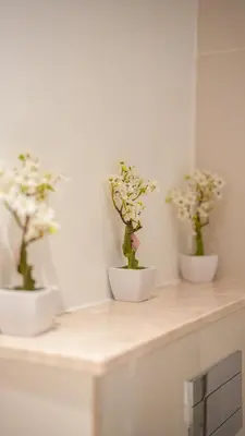 three white bowls with flowers in them on a counter at Deluxe Pool View apartment in BLVD Crescent Downtown Dubai by Norbu Holiday Homes in Dubai