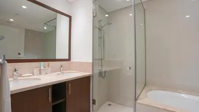 a bathroom with two sinks and a shower at Deluxe Pool View apartment in BLVD Crescent Downtown Dubai by Norbu Holiday Homes in Dubai