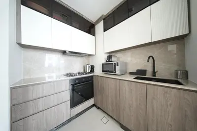 a kitchen with wooden cabinets and a microwave at Elegant 1BR with Balcony in West Five Business Bay in Dubai