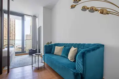 a blue couch in a living room with a large window at Frank Porter - Liv Residence in Dubai