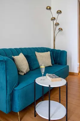 a blue couch with a glass of wine and a table at Frank Porter - Liv Residence in Dubai