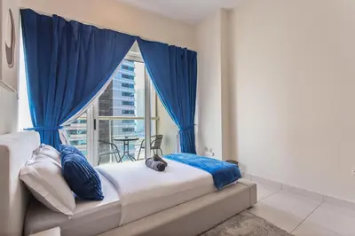 a bedroom with a bed with blue curtains and a window at Bright 2BR in Dubai Marina - Close to beach in Dubai