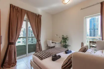 a bedroom with a couch and a large window at Bright 2BR in Dubai Marina - Close to beach in Dubai