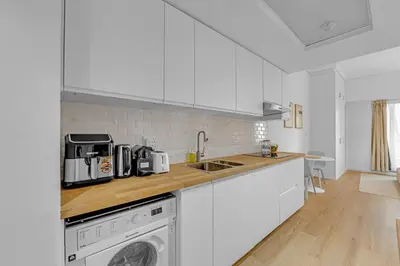 a kitchen with white cabinets and a washer and dryer at Waves - Modern Lakeview Studio - Cozy & Bright in Dubai