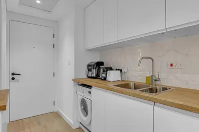 a white kitchen with a sink and a dishwasher at Waves - Modern Lakeview Studio - Cozy & Bright in Dubai