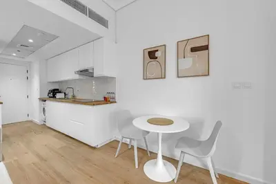 a kitchen with a table and chairs in a room at Waves - Modern Lakeview Studio - Cozy & Bright in Dubai