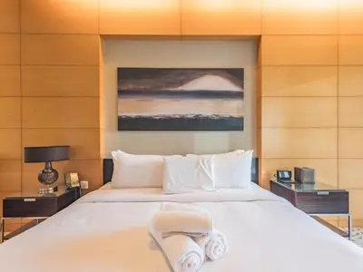 a bedroom with a large white bed and a painting at Direct Dubai Mall Access-Emaar Residences-1BR Like Home in Dubai