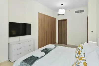 a bedroom with a large white bed with a flat screen tv at Luxury Brand New 2 BR Apartment Burj & Canal View Business Bay Dubai in Dubai