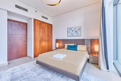 a bedroom with a large bed and a wooden door at Burj Vista Luxury Apartments with Burj Khalifa View in Dubai