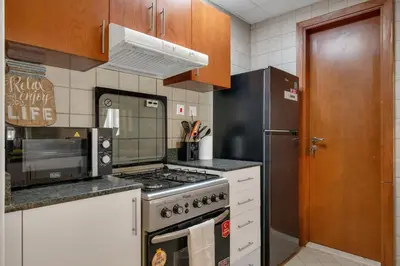 a kitchen with a stove and a refrigerator at JLT Cozy and Modern 1BR Pool and Gym Walk to Metro in Dubai