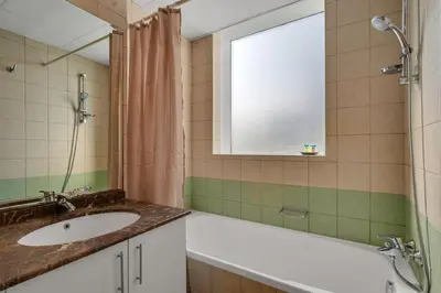 a bathroom with a sink and a tub and a window at JLT Cozy and Modern 1BR Pool and Gym Walk to Metro in Dubai