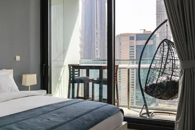 a bedroom with a bed and a large window with a swing at Burj Vista Modern Comfort - 1BR with Pool, Gym and Scenic views in Dubai