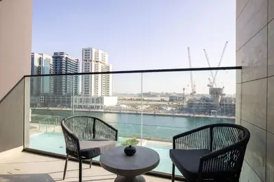 a balcony with two chairs and a table and a large window at The Trillionaire Bayhouse - Private Jacuzzi, Sauna, pool and gym in Dubai