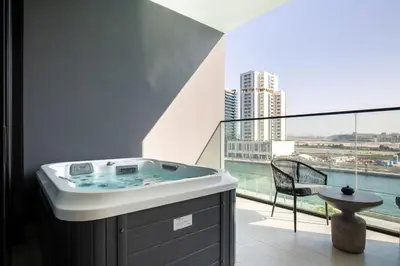 a bathroom with a tub and a balcony with a view at Trillionaire Bayhouse One- Private Jacuzzi, Sauna, pool and gym in Dubai