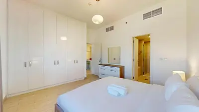 a white bedroom with a bed and white cabinets at Vacationer l Cozy 1 Bed l Jumeirah Golf Estate l Free Pool, Gym in Dubai