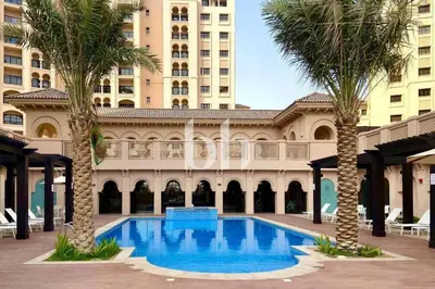 a swimming pool with palm trees in front of a building at Vacationer l Cozy 1 Bed l Jumeirah Golf Estate l Free Pool, Gym in Dubai
