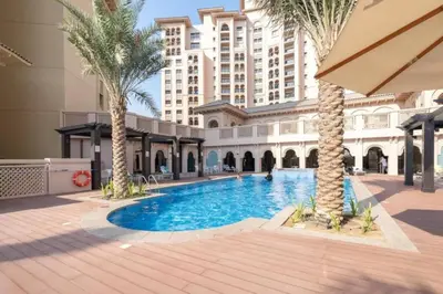 a swimming pool in the middle of a building with palm trees at Vacationer l Cozy 1 Bed l Jumeirah Golf Estate l Free Pool, Gym in Dubai