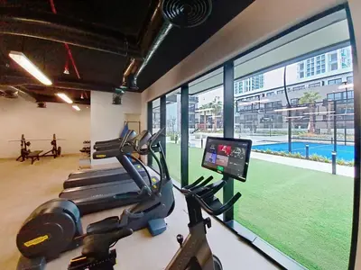 a gym with a treadmill and a view of a pool at Vacationer l Peaceful Studio l Circle Mall l Greenery Community in Dubai