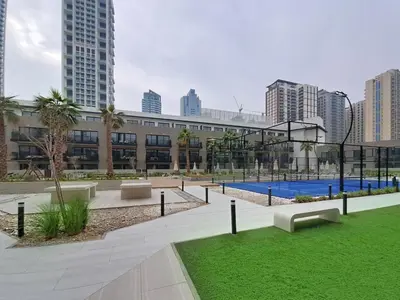 a large building with a courtyard with grass and benches at Vacationer l Peaceful Studio l Circle Mall l Greenery Community in Dubai