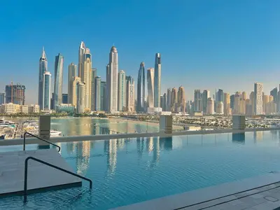 a swimming pool in front of a city skyline at Waves - Beachfront Bliss - Marina Vista 1BR Escape in Dubai