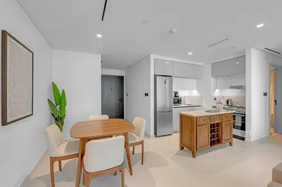 a kitchen and dining room with a wooden table and chairs at Waves - Beachfront Bliss - Marina Vista 1BR Escape in Dubai