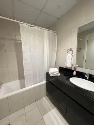 a bathroom with a tub and a sink and a mirror at Cove Luxe Holiday Home JVC in Dubai