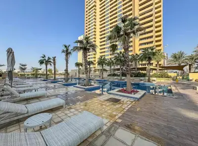 a resort with chairs and palm trees and a building at Cove Luxe Holiday Home JVC in Dubai