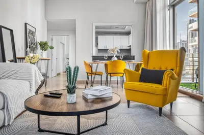 a living room with yellow chairs and a table at Modern 1BR Apartment - Burj Khalifa View - Pool & Terrace - Near Metro in Dubai