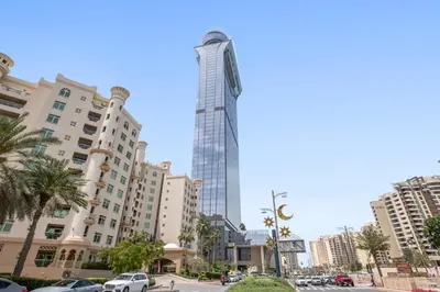 a tall building with a clock on the side of it at Luxury 1BR in The Palm Tower Near Nakheel Mall in Dubai