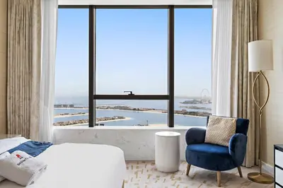 a bedroom with a bed and a chair and a large window at Luxury 1BR in The Palm Tower Near Nakheel Mall in Dubai