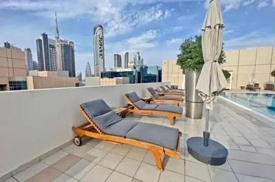 a rooftop patio with lounge chairs and an umbrella at Urban apartment near to Dubai mall & Burj Khalifa in Dubai