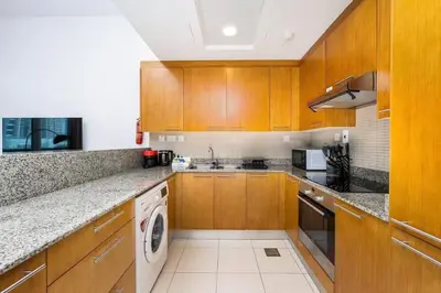 a kitchen with wooden cabinets and a washer and dryer at Urban apartment near to Dubai mall & Burj Khalifa in Dubai