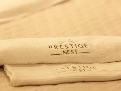 a towel with the words prestige nest written on it at Downtown Views Suites by Prestige Nest in Dubai