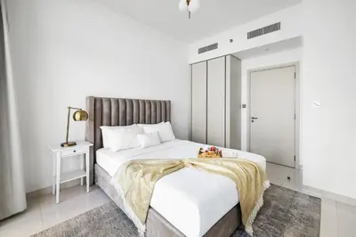 a white bedroom with a bed and a table at 2BR Beachfront Retreat with Palm and Dubai Eye Views in Dubai