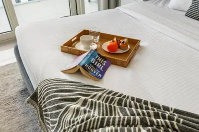 a tray with a plate of food on a bed at 2BR Beachfront Retreat with Palm and Dubai Eye Views in Dubai