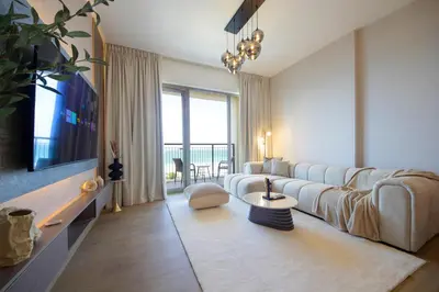 a living room with a large couch and a tv at Stylish Apartment in Le Pont Jumeirah Near Beach in Dubai