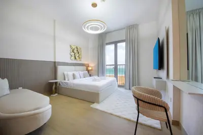 a white bedroom with a bed and a chair at Stylish Apartment in Le Pont Jumeirah Near Beach in Dubai