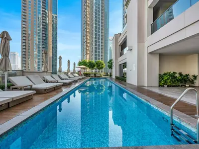 a swimming pool with chaise lounge chairs next to a building at Blissful Stays - Luxury Two Bedroom Apartment at ACT Tower 2, Boulevard, Burj Khalifa, Pool, Near Dubai Mall in Dubai