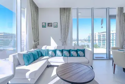 a living room with a white couch and a table at TRPS - District One Residences, MBR - Brand New 3BR plus Maids, Lagoon View, Fully Furnished in Dubai