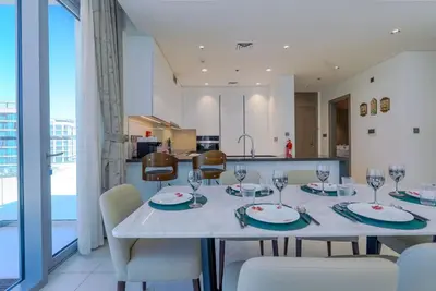 a dining room with a table and chairs and a kitchen at TRPS - District One Residences, MBR - Brand New 3BR plus Maids, Lagoon View, Fully Furnished in Dubai
