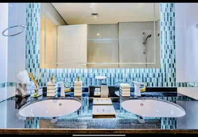 two sinks in a bathroom with blue tiles at Luxury Fendi with Stunning Marina Views in Dubai