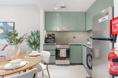 a kitchen with green cabinets and a table with chairs at Steps from the Park, Mall and The Green Planet, Minutes to Metro with Easy Access to Downtown Attractions, Myrtle, Al Wasl by Deluxe Holiday Homes in Dubai