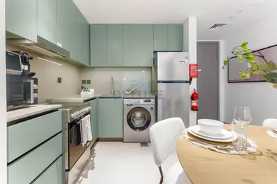 a kitchen with blue cabinets and a table with a dining room at Steps from the Park, Mall and The Green Planet, Minutes to Metro with Easy Access to Downtown Attractions, Myrtle, Al Wasl by Deluxe Holiday Homes in Dubai