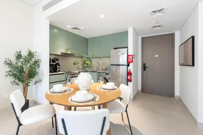 a kitchen and dining room with a wooden table and chairs at Steps from the Park, Mall and The Green Planet, Minutes to Metro with Easy Access to Downtown Attractions, Myrtle, Al Wasl by Deluxe Holiday Homes in Dubai