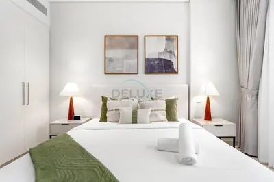 a white bedroom with a large white bed and two lamps at Steps from the Park, Mall and The Green Planet, Minutes to Metro with Easy Access to Downtown Attractions, Myrtle, Al Wasl by Deluxe Holiday Homes in Dubai