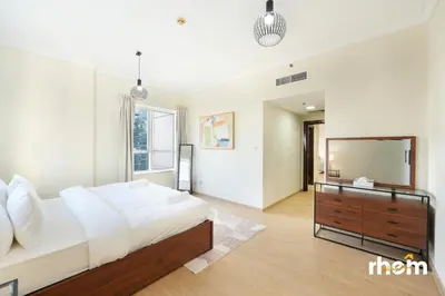 a bedroom with a large white bed and a dresser at Brand New 2-BR Panoramic View - Near Marina & JBR in Dubai