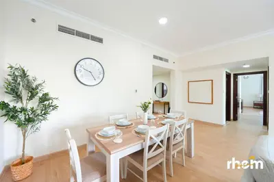 a dining room with a table and a clock on the wall at Brand New 2-BR Panoramic View - Near Marina & JBR in Dubai