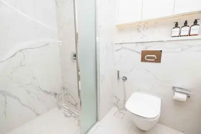 a white bathroom with a toilet and a shower at Bright Studio with Pool Access - Azizi Riviera in Dubai