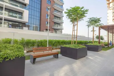 a park with a bench and trees and buildings at Bright Studio with Pool Access - Azizi Riviera in Dubai